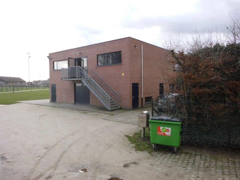 Zijkant van het bakstenen Chirogebouw met buitentrap